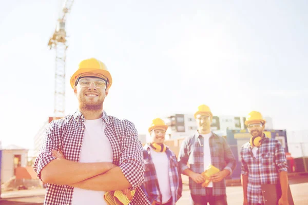Group of smiling builders in hardhats outdoors — Stock Photo, Image