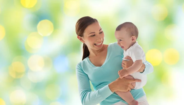 Gelukkig moeder met kleine baby over groene lichten — Stockfoto