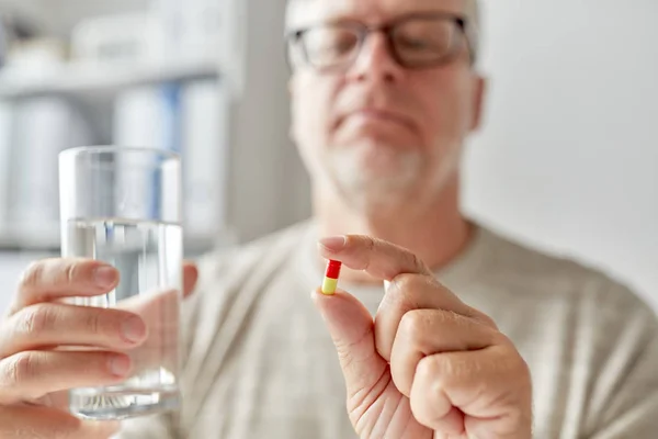 Närbild av gamla mannen händerna med piller och vatten — Stockfoto