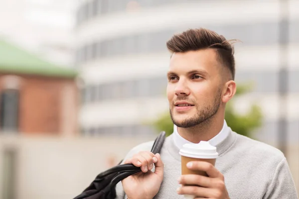 Young man with bag drinking coffee in city — Stock Photo, Image