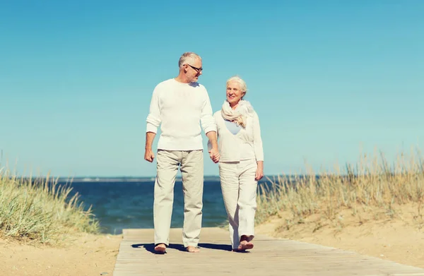 Feliz pareja de ancianos tomados de la mano en verano playa — Foto de Stock