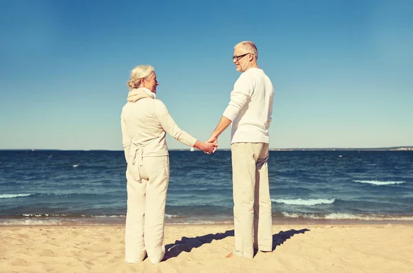 Feliz pareja de ancianos cogidos de la mano verano playa — Foto de Stock