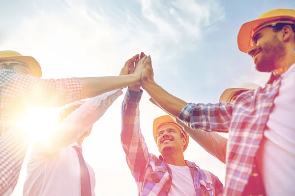 Närbild av byggare i hardhats att göra high five — Stockfoto