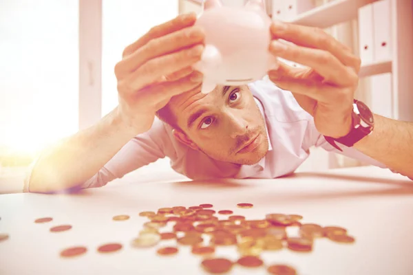 Hombre de negocios con alcancía y monedas en la oficina — Foto de Stock