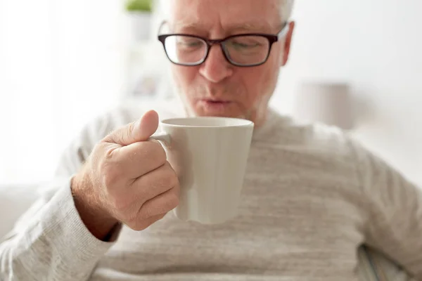 Glücklicher Senior, der zu Hause Tee oder Kaffee trinkt — Stockfoto