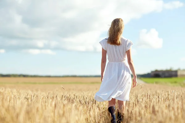 Mujer joven en vestido blanco caminando por el campo — Foto de Stock