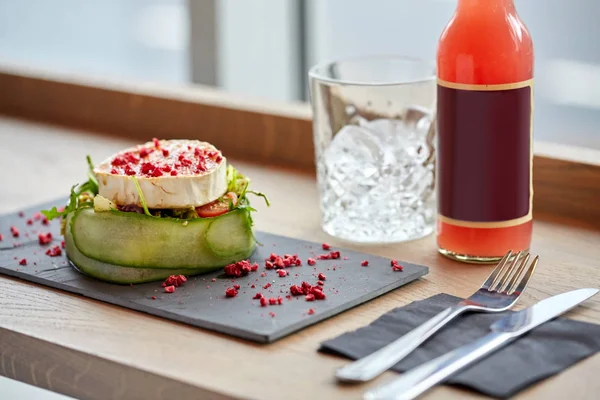 Salada, garrafa de bebida, vidro e talheres na mesa — Fotografia de Stock