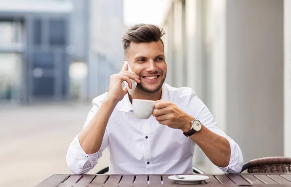 Hombre con café llamando en el teléfono inteligente en la cafetería de la ciudad — Foto de Stock