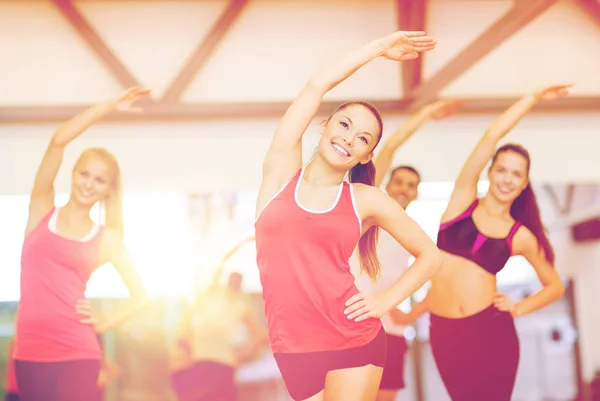 Groep glimlachende mensen die zich uitstrekt in de sportschool — Stockfoto