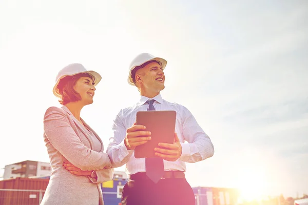 Glad byggare i hardhats med TabletPC utomhus — Stockfoto