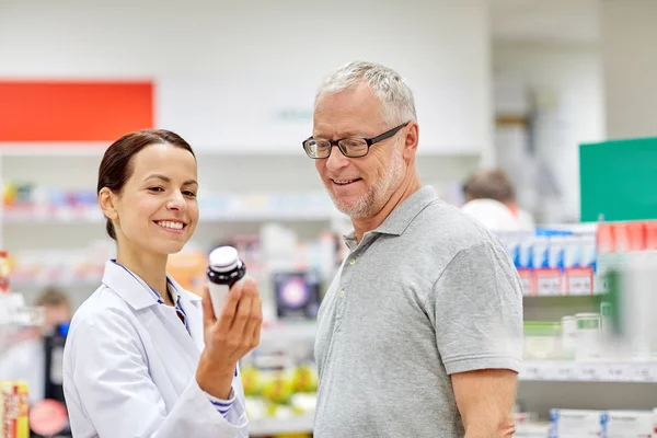 Farmacéutico mostrando droga al hombre mayor en la farmacia — Foto de Stock