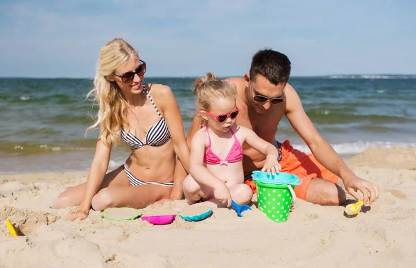 Glückliche Familie spielt mit Sandspielzeug am Strand — Stockfoto