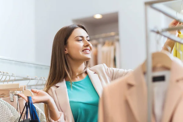 Feliz jovem mulher escolhendo roupas no shopping — Fotografia de Stock