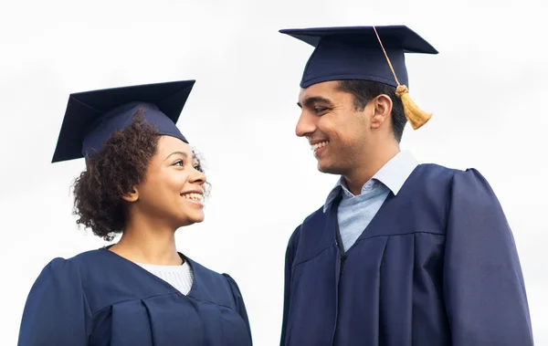 Happy students or bachelors in mortar boards — Stock Photo, Image