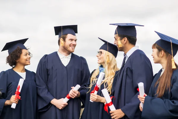 Estudantes felizes em placas de argamassa com diplomas — Fotografia de Stock