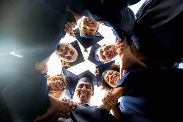 Happy students or bachelors in mortar boards — Stock Photo, Image