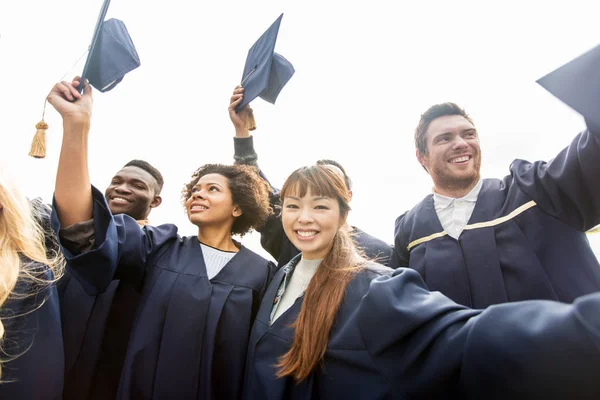 Glückliche Studenten oder Junggesellen, die mit Mörtelbrettern wedeln — Stockfoto