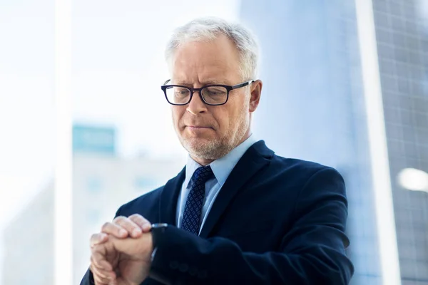 Senior affärsman kontrollerar tiden på sitt armbandsur — Stockfoto