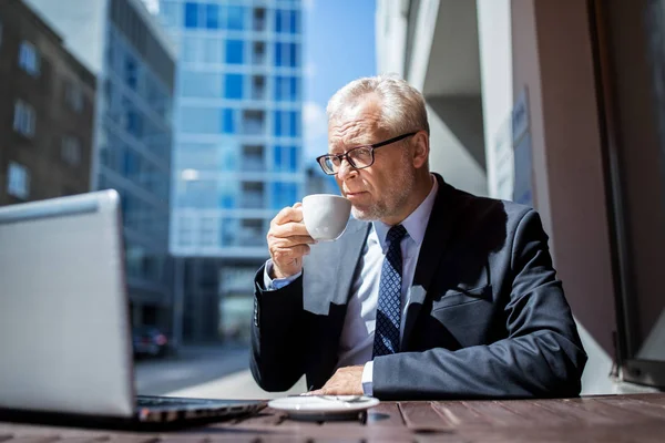 Senior businessman with laptop drinking coffee — Stock Photo, Image