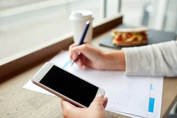 Vrouw met smartphone en papieren formulier in café — Stockfoto