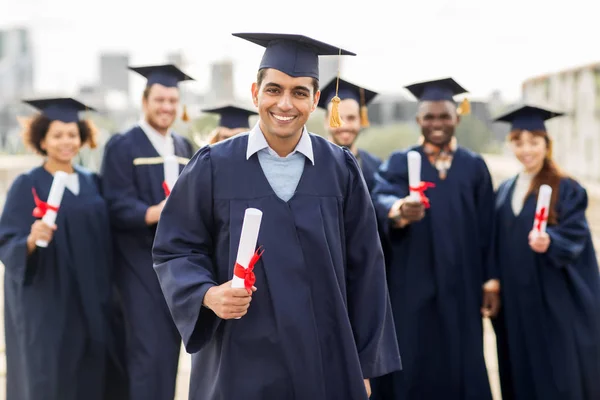 Estudiantes felices en morteros con diplomas — Foto de Stock