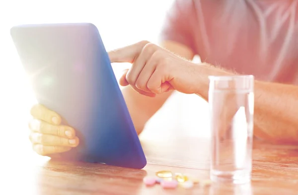 Primer plano de las manos con la tableta de la PC, pastillas y agua — Foto de Stock