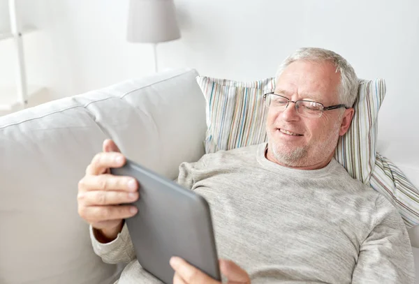 Uomo anziano con tablet pc sdraiato sul divano di casa — Foto Stock