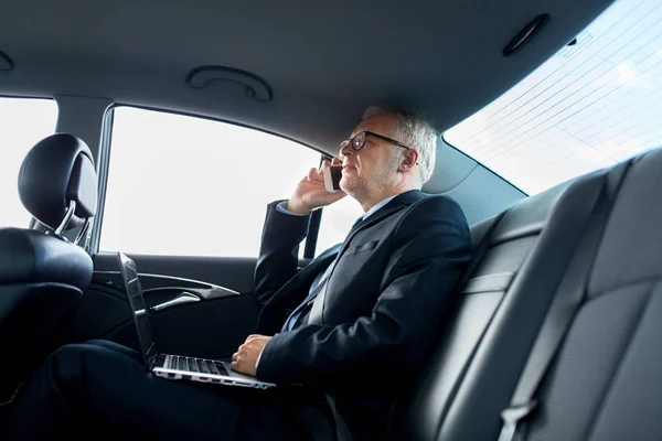 Empresário sênior chamando no smartphone no carro — Fotografia de Stock