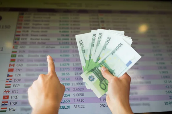 Hands with euro money over currency exchange rates — Stock Photo, Image