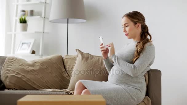 Gelukkig zwanger vrouw met smartphone thuis — Stockvideo