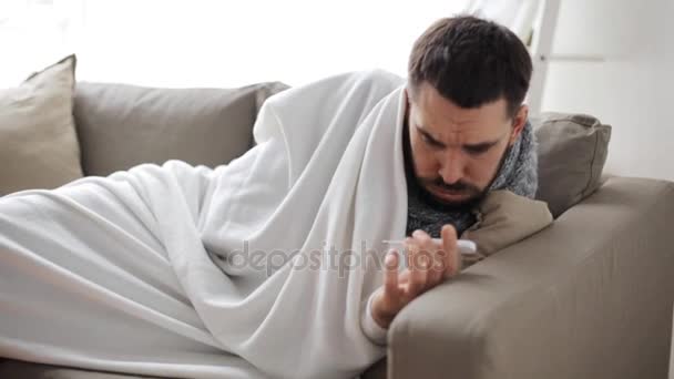 Ill man with thermometer having flu at home — Stock Video