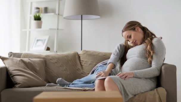 Счастливая беременная женщина и девочка на диване дома — стоковое видео