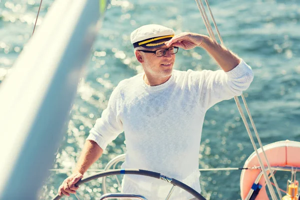 Senior man op roer op boot of jacht zeilen in zee — Stockfoto