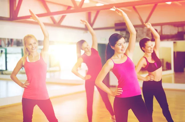 Group of smiling people stretching in the gym — Stock Photo, Image