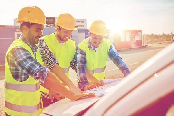 Close up of builders with blueprint on car hood — Stock Photo, Image