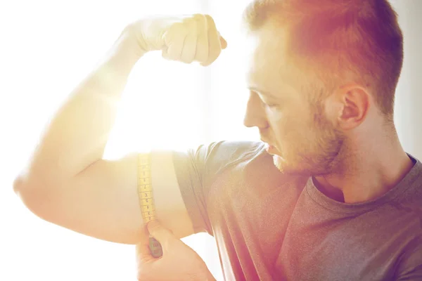 Close up van mannelijke handen met tape meten biceps — Stockfoto
