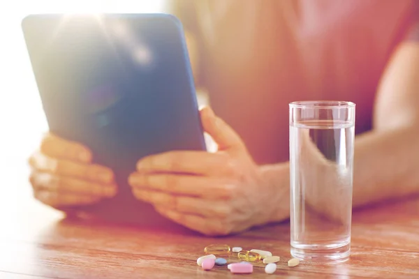 Primer plano de las manos con la tableta de la PC, pastillas y agua — Foto de Stock