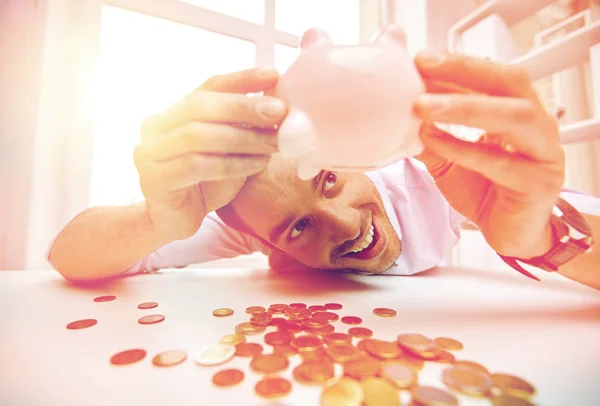 Affärsman med spargris och mynt på kontor — Stockfoto