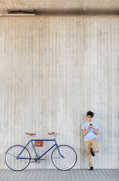 Hombre con teléfono inteligente y bicicleta de engranaje fijo en la calle —  Fotos de Stock