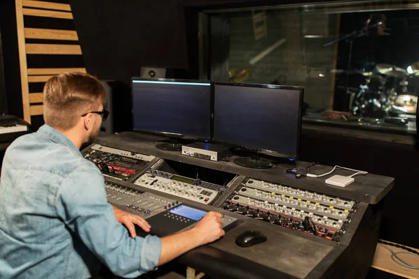 man at mixing console in music recording studio