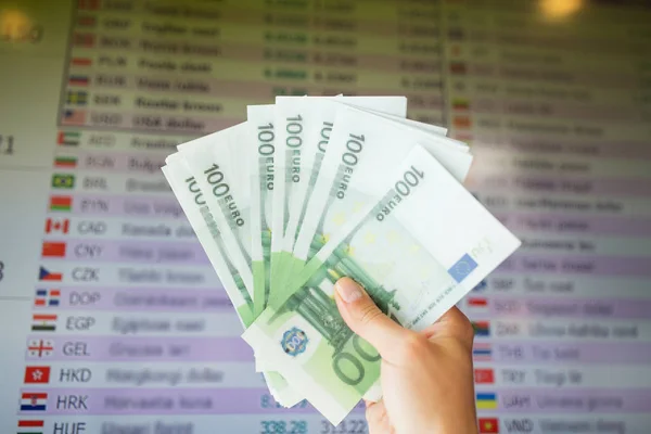 Χέρι με ευρώ χρήματα πάνω από τις συναλλαγματικές ισοτιμίες — Φωτογραφία Αρχείου