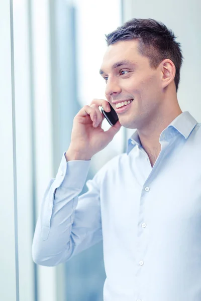 Homme d'affaires souriant avec smartphone au bureau — Photo