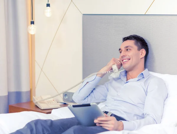 Businessman with tablet pc and phone in hotel room — Stock Photo, Image