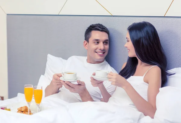 Uśmiechający się para o śniadanie w łóżku w hotelu — Zdjęcie stockowe
