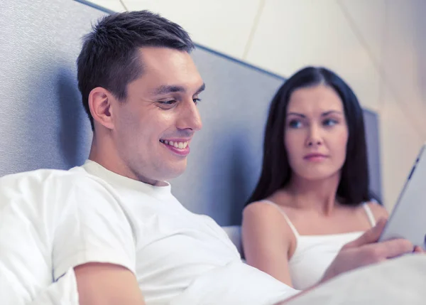 Lachende paar in bed met tablet pc-computers — Stockfoto