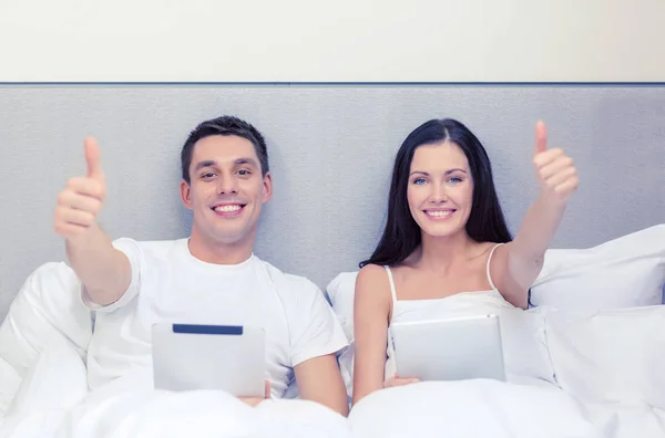 タブレット pc コンピューターとベッドの中で笑顔のカップル — ストック写真