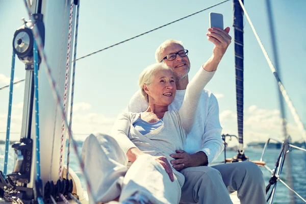 Seniorzy z smartphone przy selfie na jachcie — Zdjęcie stockowe