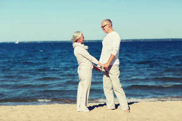 Feliz pareja de ancianos tomados de la mano en verano playa — Foto de Stock