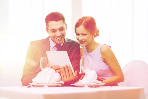 Pareja con menús en la tableta PC en el restaurante — Foto de Stock