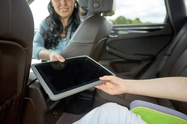Mujer que da la tableta PC a su hijo en el coche — Foto de Stock